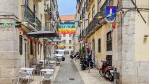 A narrow cobblestone street with outdoor seating and a PAZ banner. - Trendy Loft Heart Of The City! (Lisbon)