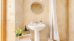 A bathroom with a white pedestal sink, a round mirror, and a shower curtain. - Top Location Beautiful Apartment! (Lisbon)