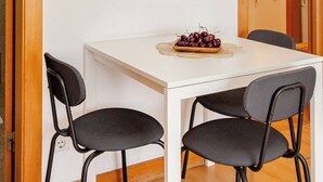 A dining area with a white table, two black chairs, and a plate of cherries. - Top Location Beautiful Apartment! (Lisbon)