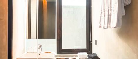 A bathroom with a sink, mirror, towel rack, and window.