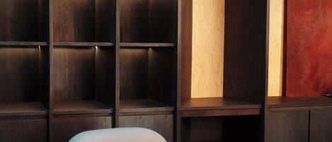 A modern room with a built-in shelving unit, a cushioned seating area, and a large abstract painting on the wall.