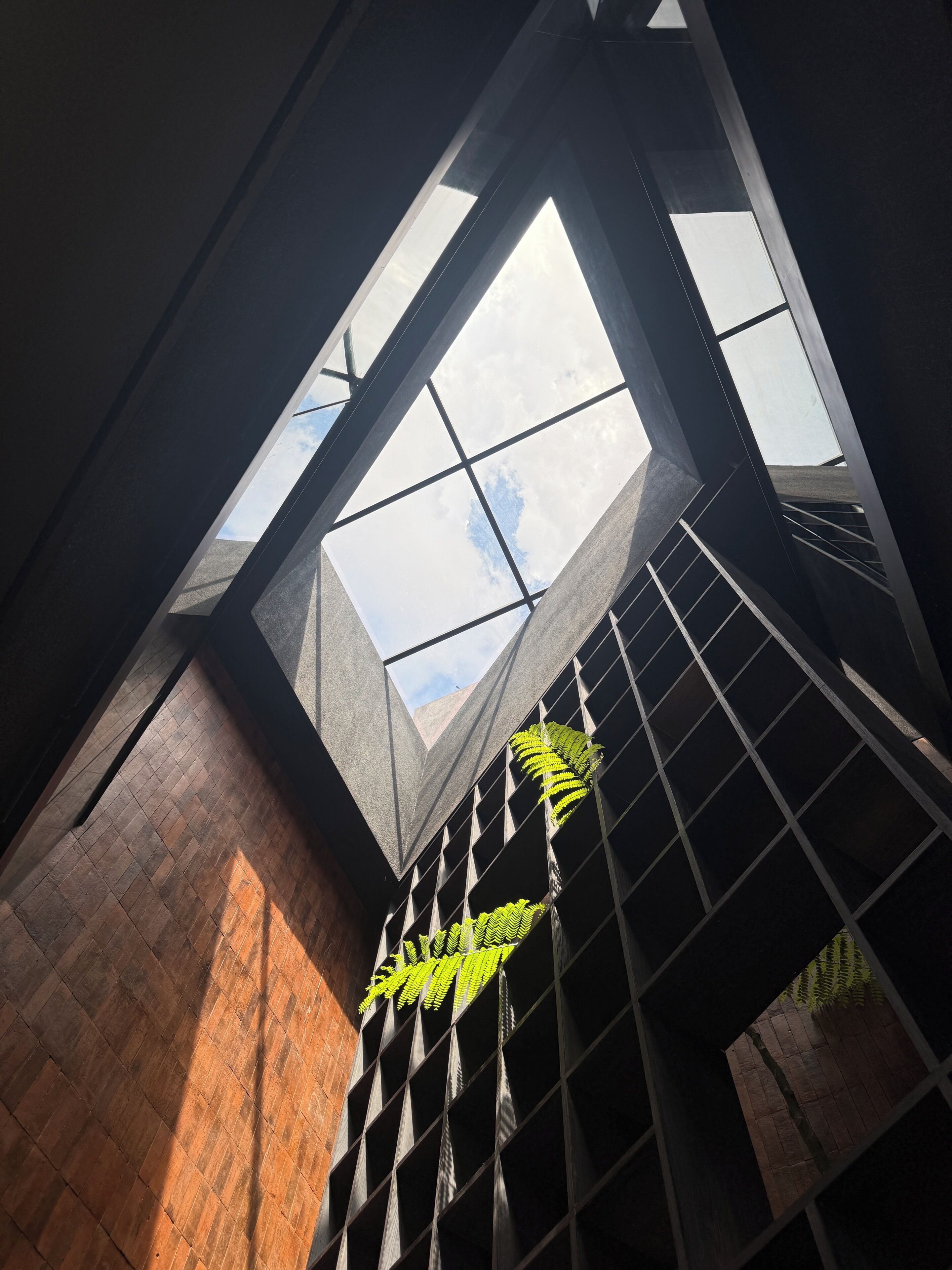 A modern architectural structure with a skylight, metal beams, and a brick wall.