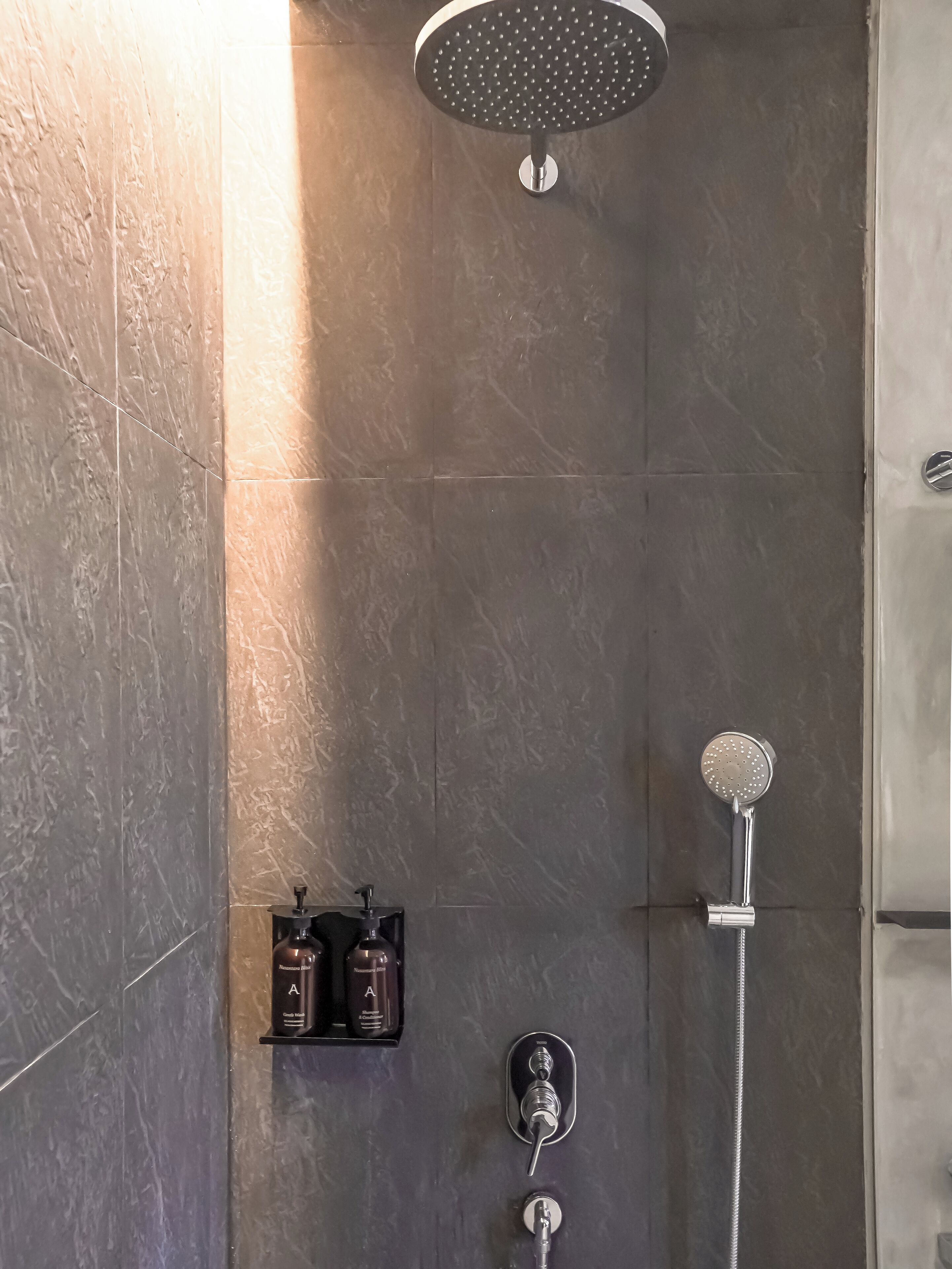 A modern shower with a handheld showerhead and a wall-mounted rain showerhead.