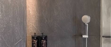 A modern shower with a handheld showerhead and a wall-mounted rain showerhead.