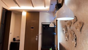Un hall de hotel con puerta de madera, una máquina de café y una lámpara fijada a la pared.