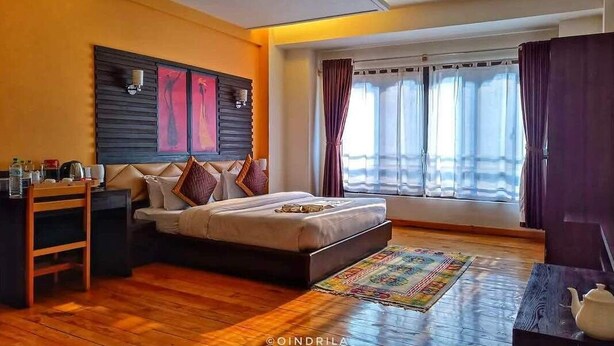 A modern hotel room with a bed, bedside table, and a view of the outdoors. - Hotel White Tara (Thimphu)