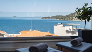 Un balcón con vista al mar, una planta y dos sillas de playa con toallas.