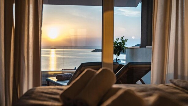 Una cama con vista al mar al atardecer.
