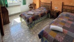 Une chambre avec deux lits, une chaise, un radiateur et une fenêtre avec des rideaux.