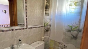 Une salle de bain équipée d’un lavabo, de toilettes et d’un rideau de douche.