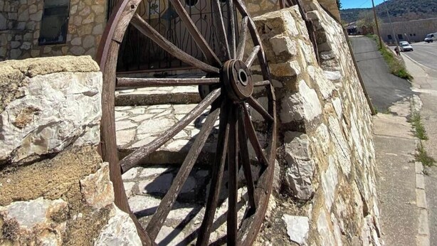 Un bâtiment en pierre avec une grande roue en bois fixée sur son côté.