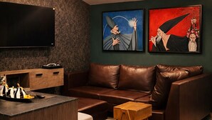 A modern living room with a brown leather sofa, a wooden coffee table, and a flat-screen TV mounted on the wall. There are two framed artworks on the wall and a ceiling light fixture. - Casa Niagara discovers this luxury place for you (Juárez)
