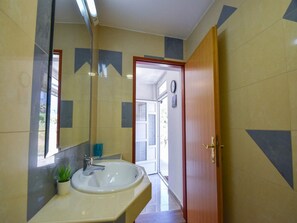 Un bagno con lavandino, specchio e porta che dà su un'altra stanza.