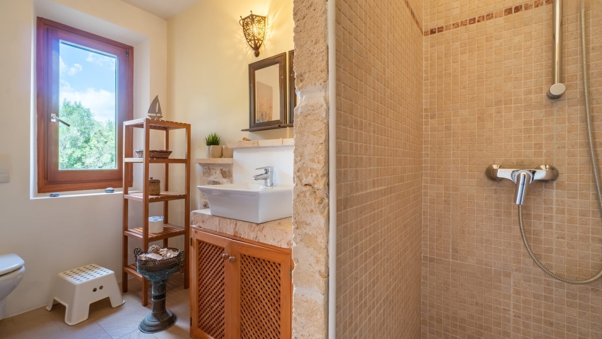 Une salle de bain avec une douche, une fenêtre, un lavabo, une étagère et des toilettes.