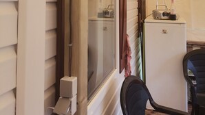 Ein kleines Zimmer mit Holzboden, einem weißen Kühlschrank, einem Radio und einer Flasche darauf.