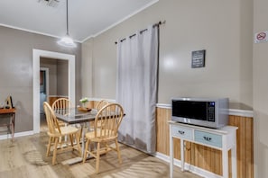 A dining area with a table and chairs, a microwave on a cabinet, and a 'No Smoking' sign on the wall.
