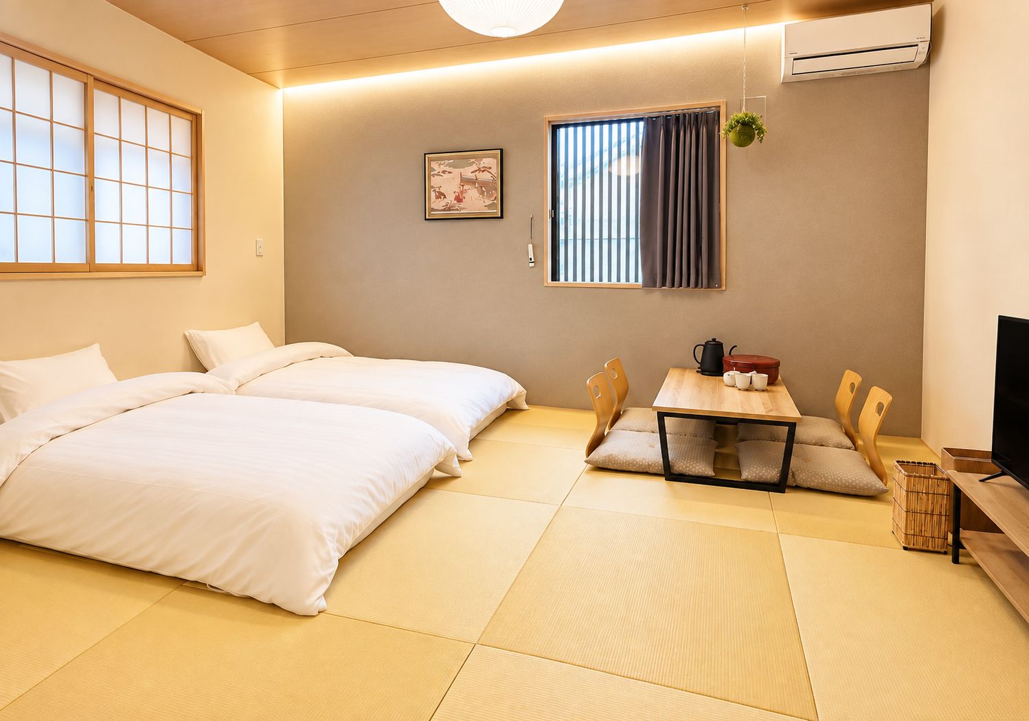 Una habitación de hotel con suelo de tatami, una cama, una pequeña mesa con sillas, un televisor y un equipo de aire acondicionado.
