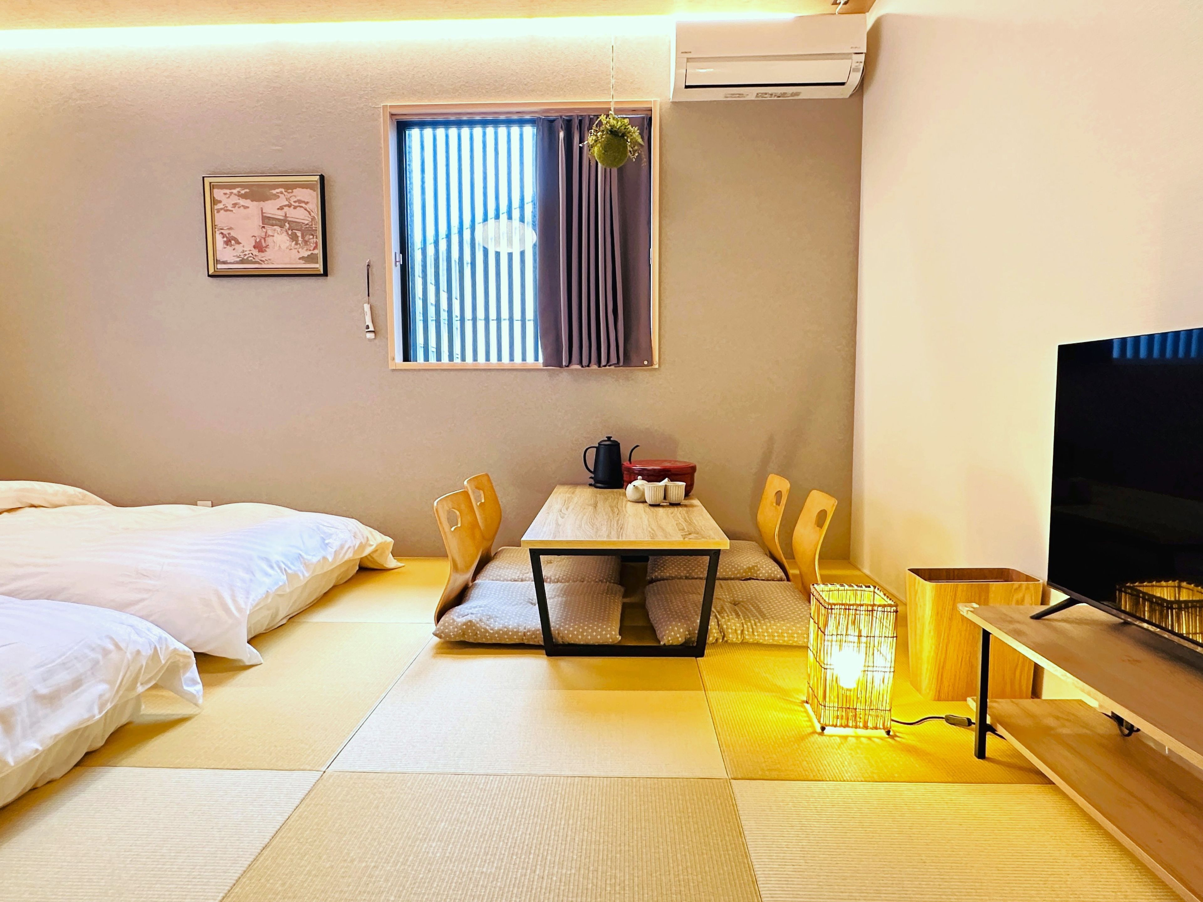 Una habitación de hotel con una cama, una mesa de comedor con sillas, un televisor y un aire acondicionado.