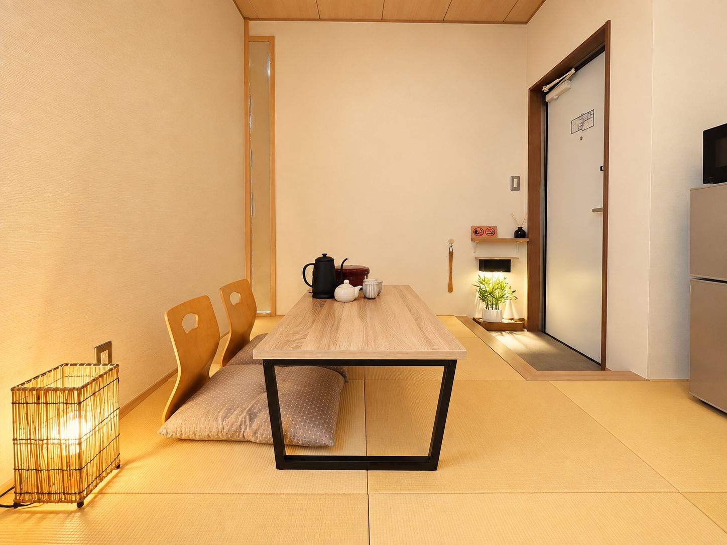 Quarto minimalista com mesa de jantar de madeira, cadeiras, pequena área de cozinha e porta deslizante.