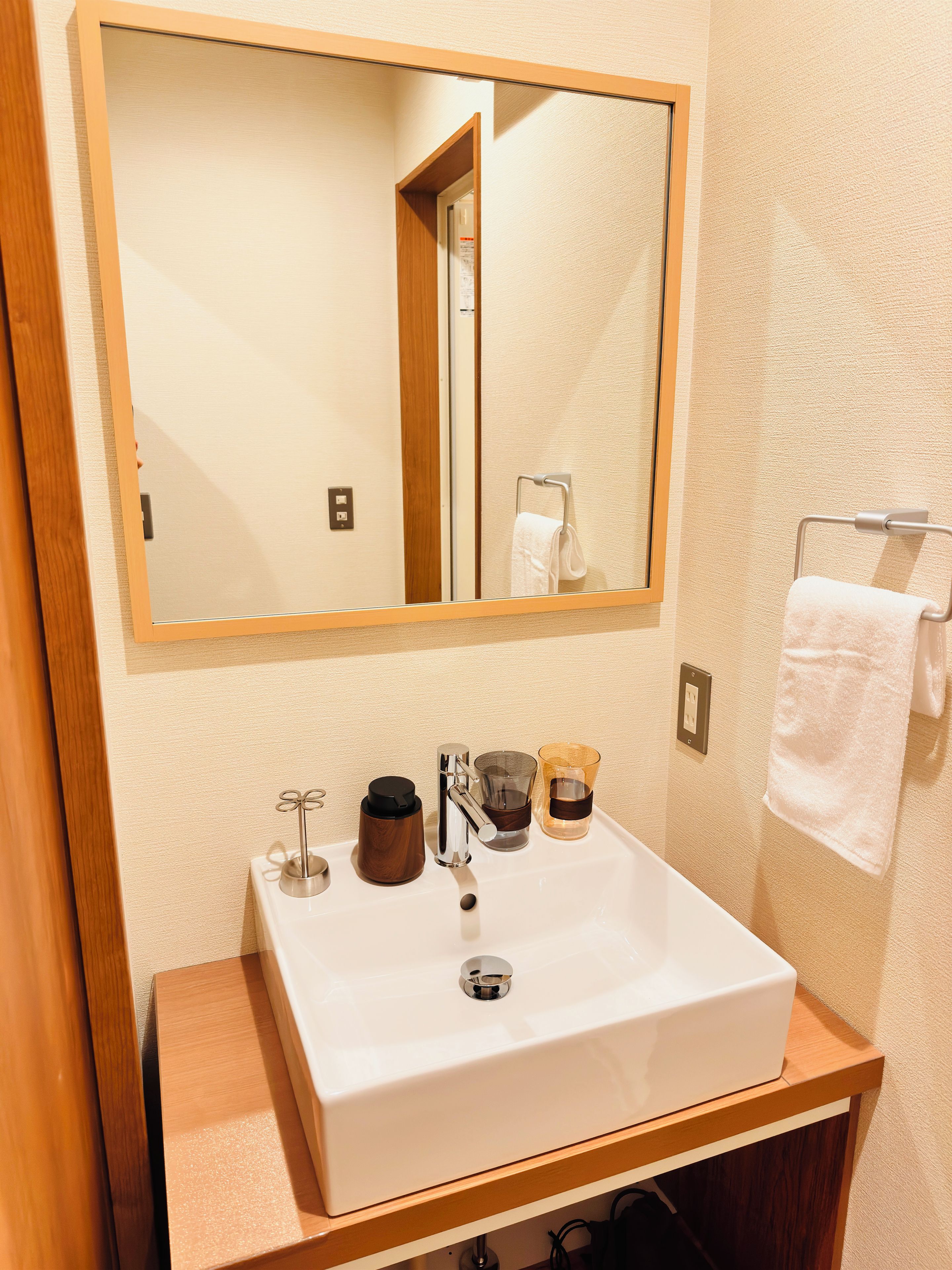 A bathroom with a white sink, a mirror, and a towel rack.