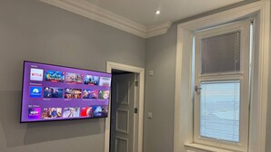 A room with a flat-screen TV displaying various streaming services, a door leading to another room, and a window with blinds. - Laurieston Inn - Exclusive double en-suite room (Laurieston)