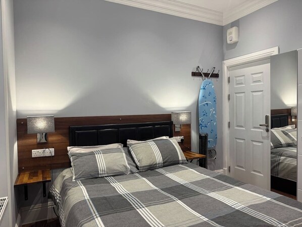 A bedroom with a bed, nightstands, a mirror, and a door. - Exclusive En-suite rooms (Laurieston)