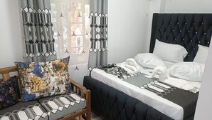 Ein Schlafzimmer mit einem Bett, einer Holzbk und einem Fenster mit Vorhängen.