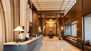 Vestíbulo de hotel con mostrador de recepción, zona de estar e iluminación decorativa.