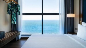 Habitación de hotel con una cama grande, televisión, escritorio y vistas al océano.