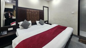 Een moderne hotelkamer met een groot bed, twee nachtkastjes, een spiegel en een rode plaid.