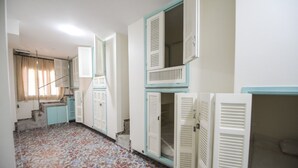 Una habitación con alfombra estampada, una escalera y un ventanal con cortinas.