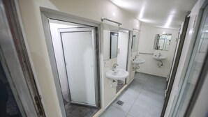 Un baño moderno con cabina de ducha de vidrio, dos lavamanos y un espejo grande.
