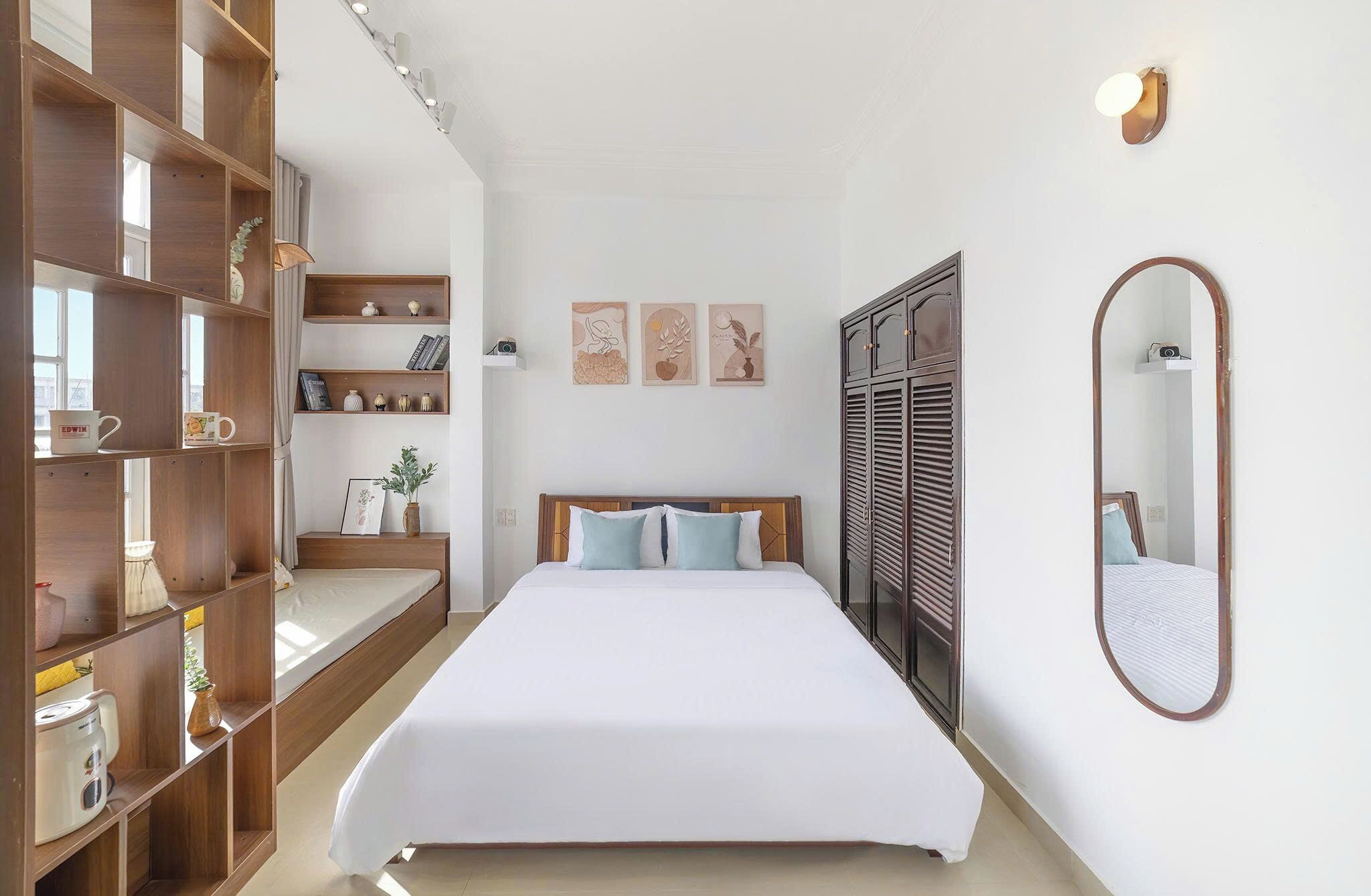 A bedroom with a bed, wooden shelving, a wardrobe, and a mirror.