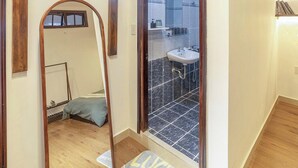 Ein Zimmer mit Holzboden, einem großen Spiegel, einer Tür zum Balkon und einem kleinen Tisch mit Stuhl.