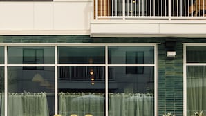 Zona junto a la piscina con mobiliario exterior y vista a un edificio con amplias ventanas y un balcón.