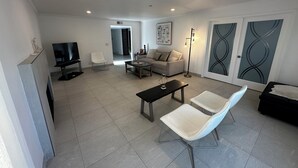 A modern living room with a sofa, two armchairs, a coffee table, a TV, and a floor lamp. - Grand House in Mt. Helix (El Cajon)