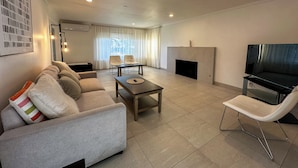 A modern living room with a sofa, chairs, a coffee table, a fireplace, and a TV. - Grand House in Mt. Helix (El Cajon)