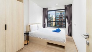 Una habitación de hotel moderna con una cama, una mesita y un armario.