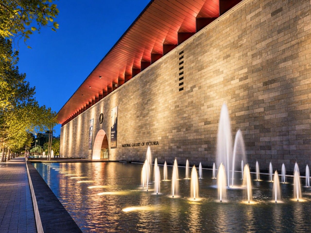 A building with a brick facade and a fountain in front.