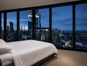 A bedroom with a large window overlooking a cityscape at night. - Skyline Suites | Stunning City Views, Gym & Pool (Southbank)
