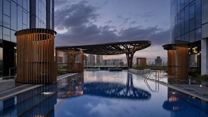 A modern building with a reflective pool, large wooden cylindrical structures, and a unique architectural canopy. - Skyline Suites | Stunning City Views, Gym & Pool (Southbank)
