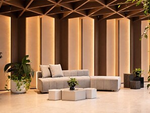 A modern living room with a sectional sofa, a coffee table, and potted plants. - Skyline Suites | Stunning City Views, Gym & Pool (Southbank)