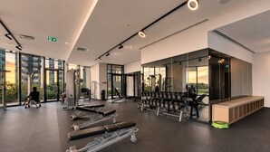 Et moderne fitnesscenter med træningsudstyr, store vinduer og udsigt til det fri.