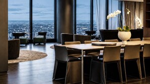Een moderne eetruimte met uitzicht over de stad, grote ramen en een centrale tafel met stoelen.