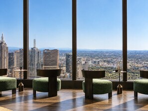 Un intérieur situé dans un immeuble de grande hauteur, doté de grandes fenêtres offrant une vue sur la ville, de meubles modernes et d'un plancher en bois poli.