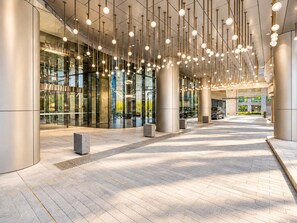 A modern building entrance with a glass facade, hanging spherical lights, and a paved walkway. - Skyline Suites | Cosy Study Suite, Australia 108 (Southbank)