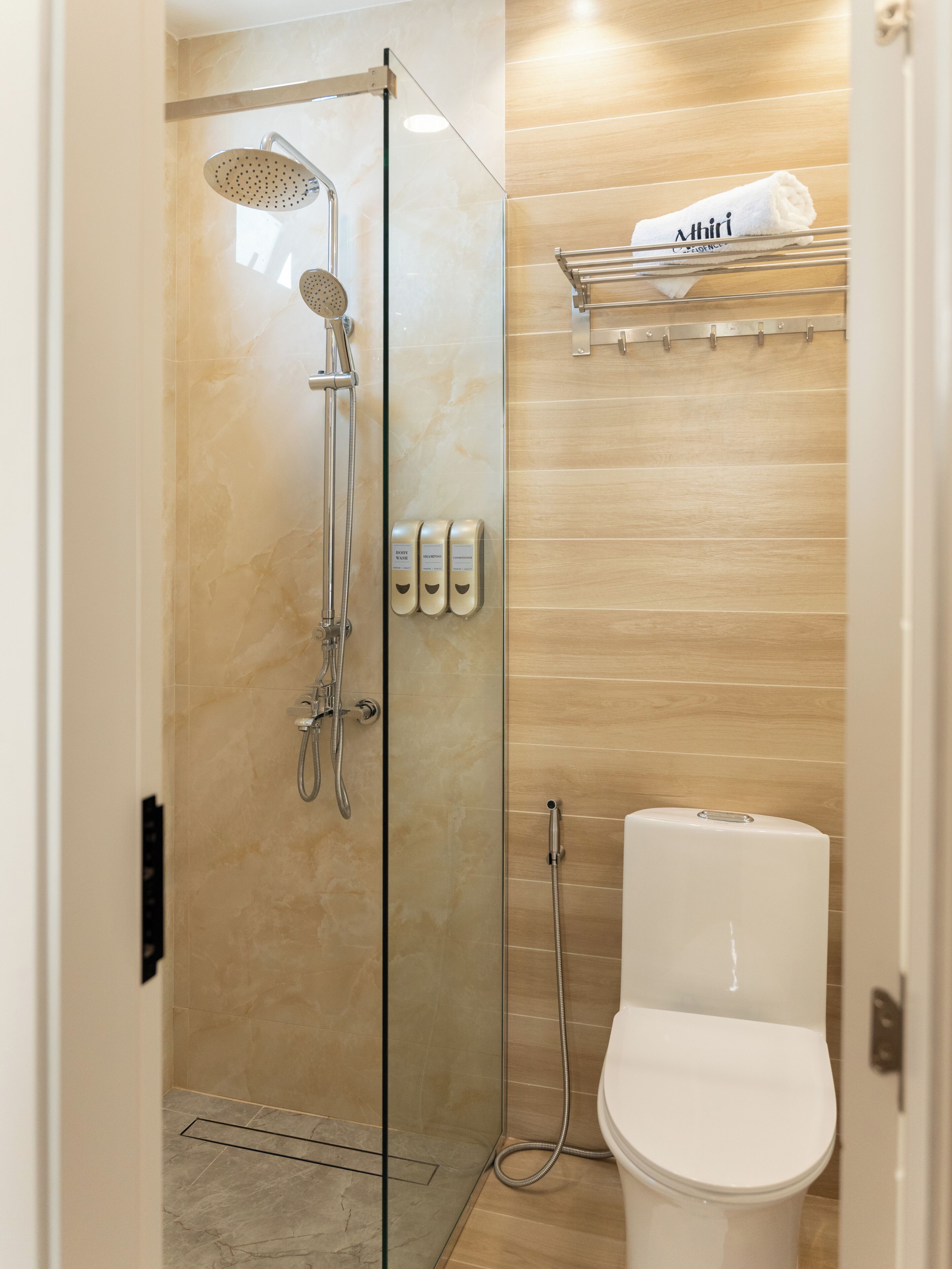 Un baño moderno con ducha de vidrio, inodoro y toallero con una toalla doblada.