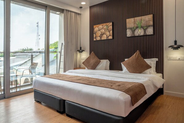 A modern hotel room with a large bed, a balcony with a view, and two artworks on the wall.
