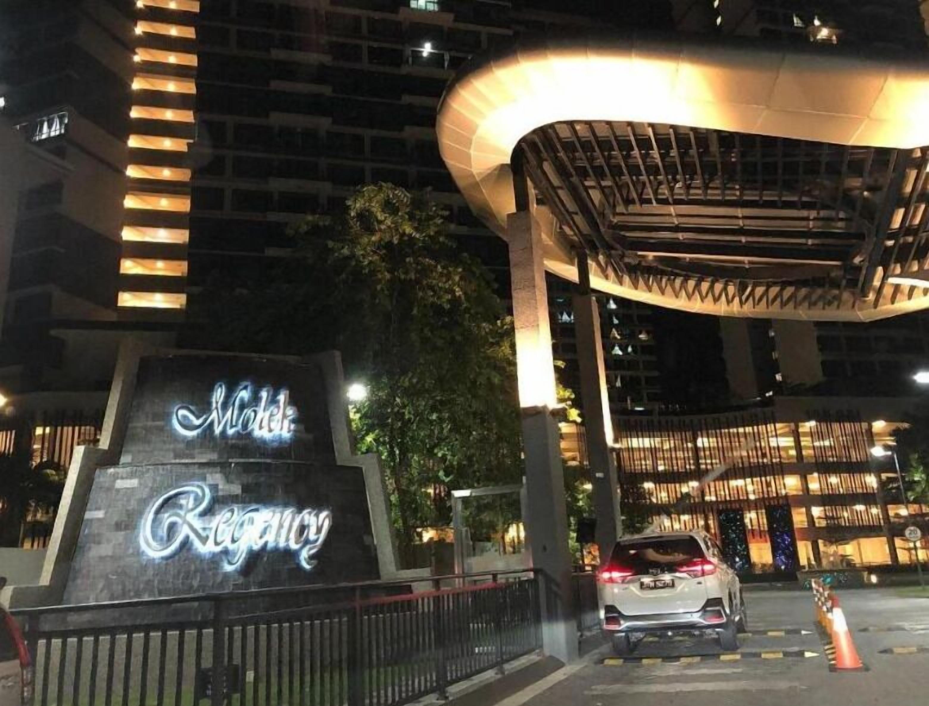 A hotel entrance with a sign reading "Hotel Regency" and a modern architectural structure above it.
