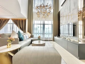 En moderne stue med sofa, sofabord og et stort fladskærms-tv på væggen.